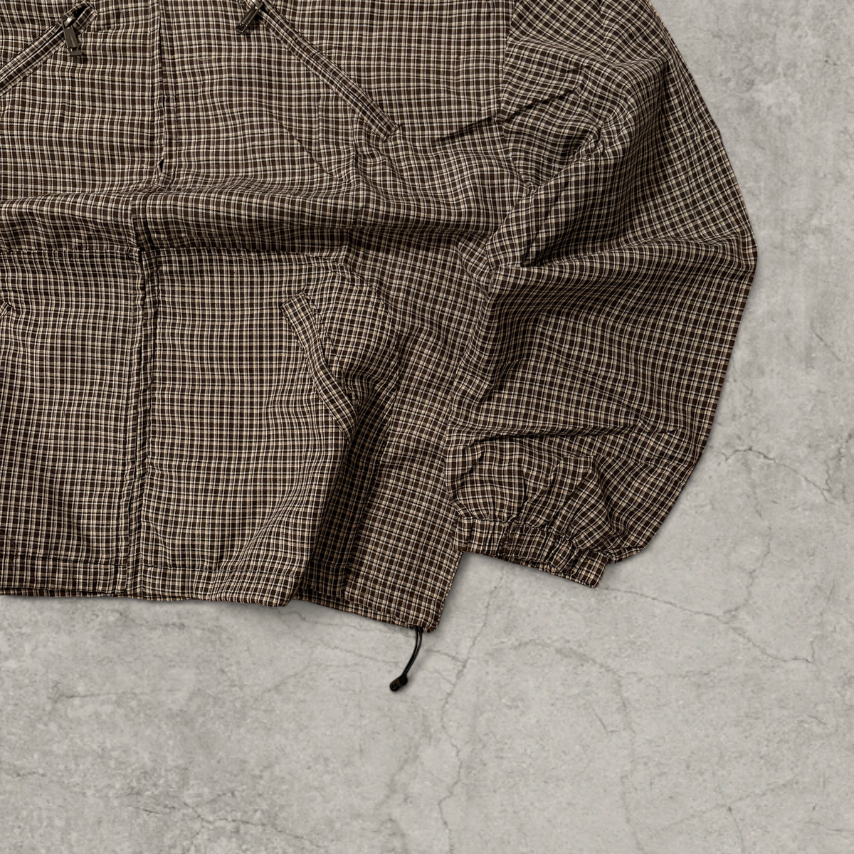 Black and brown checkered gorpcore jacket hood and zip.