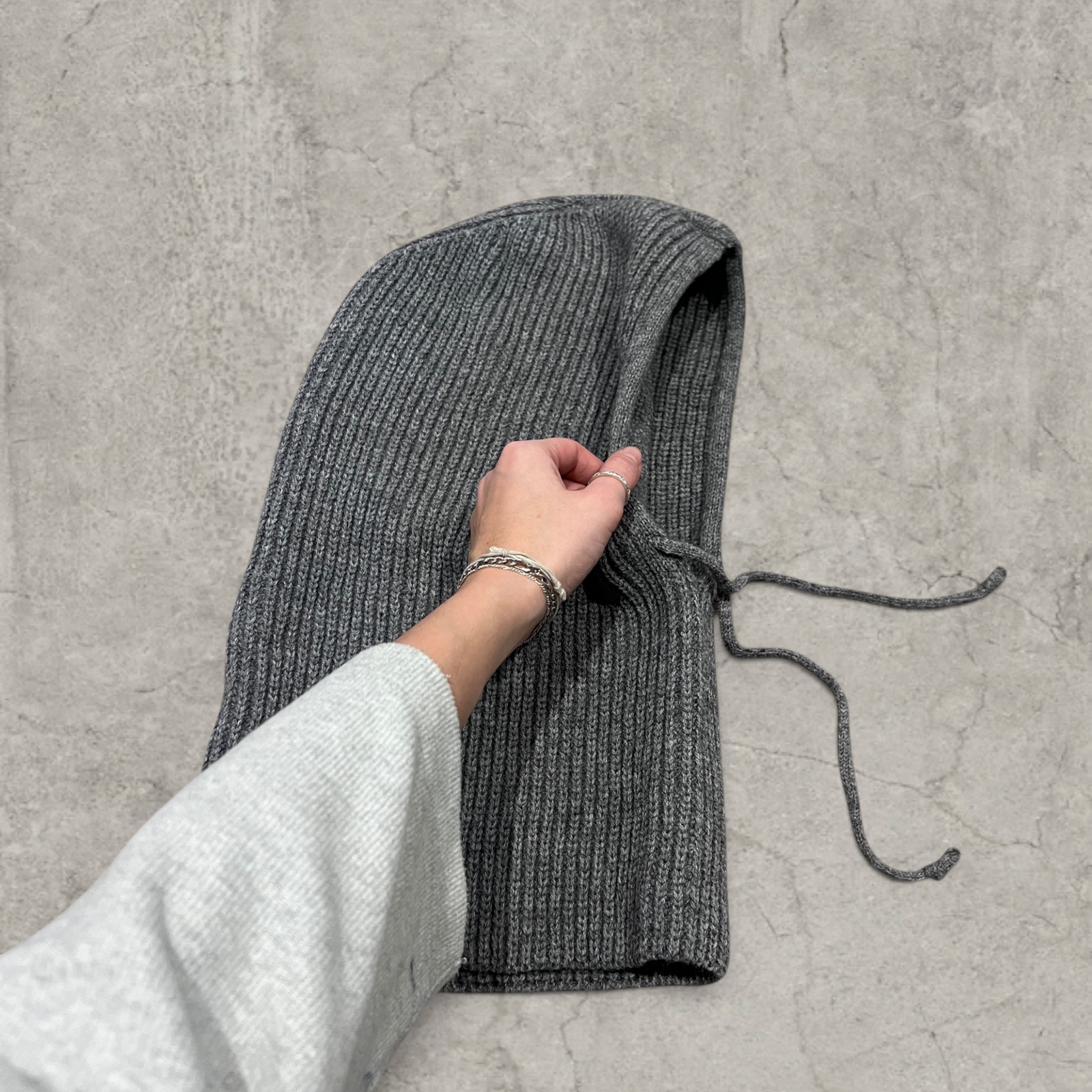 Grey knitted hooded snood scarf bonnet hat with drawstring.