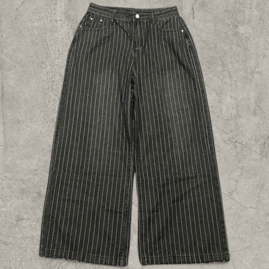 Front view of washed black wide-leg jeans with white pinstripe and raw hems laid flat on concrete surface