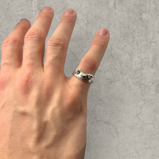 Hand wearing adjustable silver stainless steel ring with frog face design on ring finger