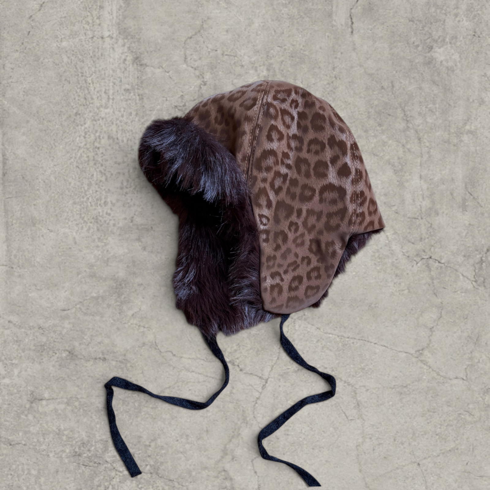 Russian trapper bonnet hat in beige animal leopard print with brown fur.