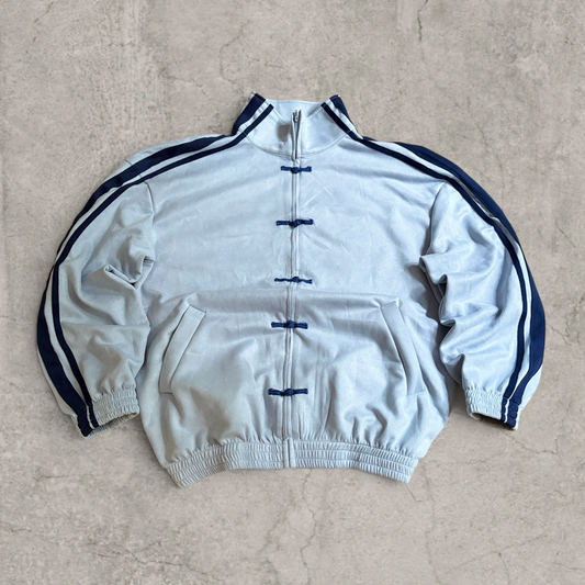 Light blue boxy Korean sweatshirt jumper with navy stripes down sleeves and navy prints on front, laid flat on concrete background