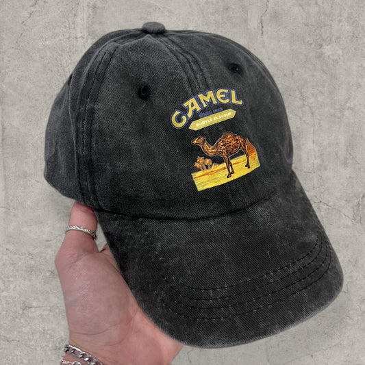 Black vintage style baseball cap with yellow camel logo held in hand showing front and curved brim