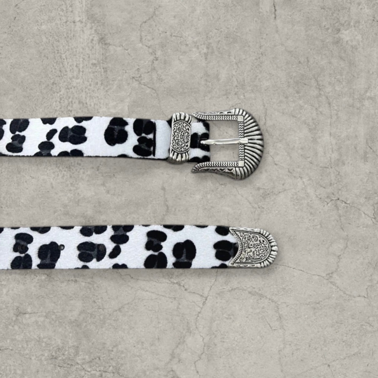 Vintage style faux leather western cowboy belt in white/black leopard print with silver trim.