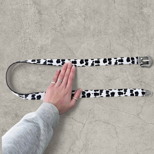 White and black leopard print faux leather western cowboy belt laid flat with silver buckle and tip