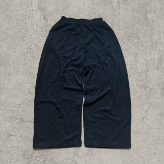 Black super baggy wide leg corduroy trousers laid flat on a grey surface