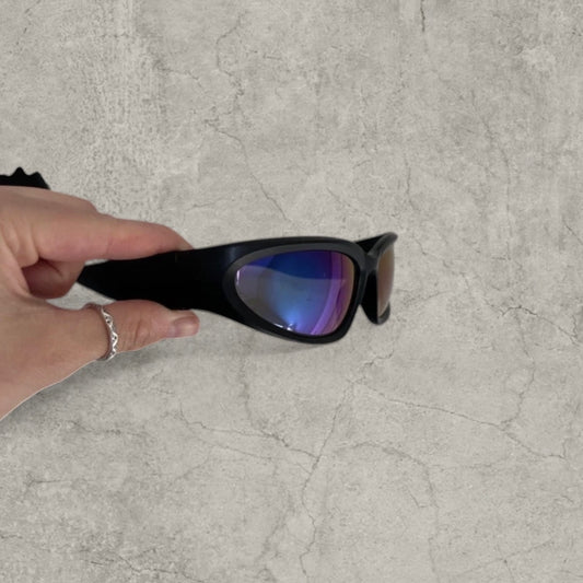 Black insane alien sunglasses with reflective blue purple lenses shown from the front held by a hand