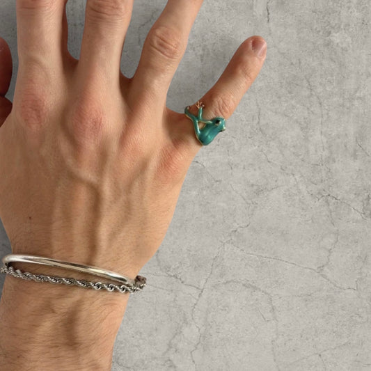 Hand wearing novelty blue and gold frog shaped adjustable ring on pinky finger