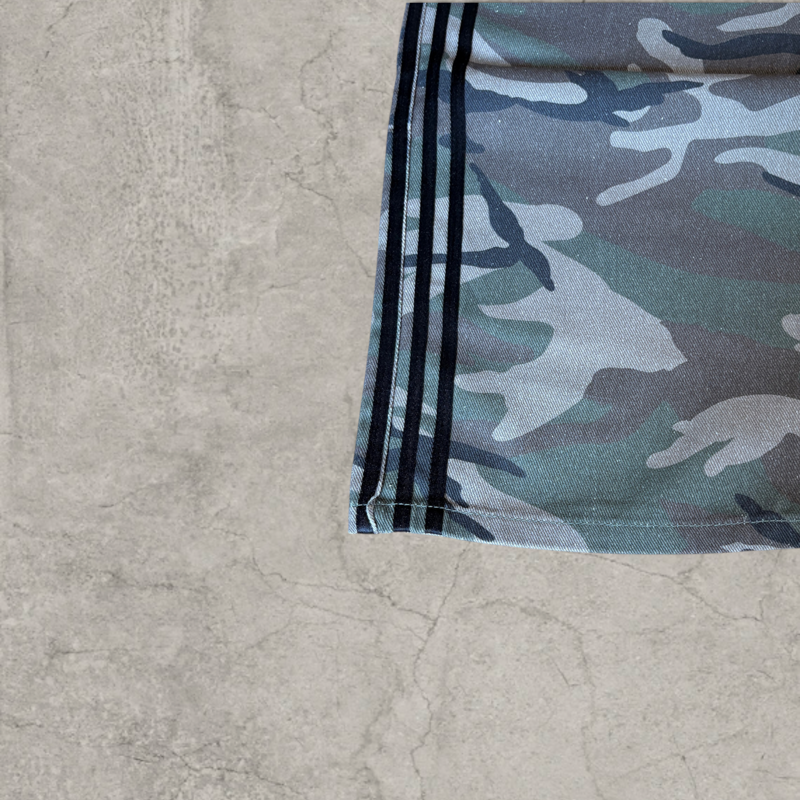 Wide-leg skater jeans with camouflage print and black stripes.