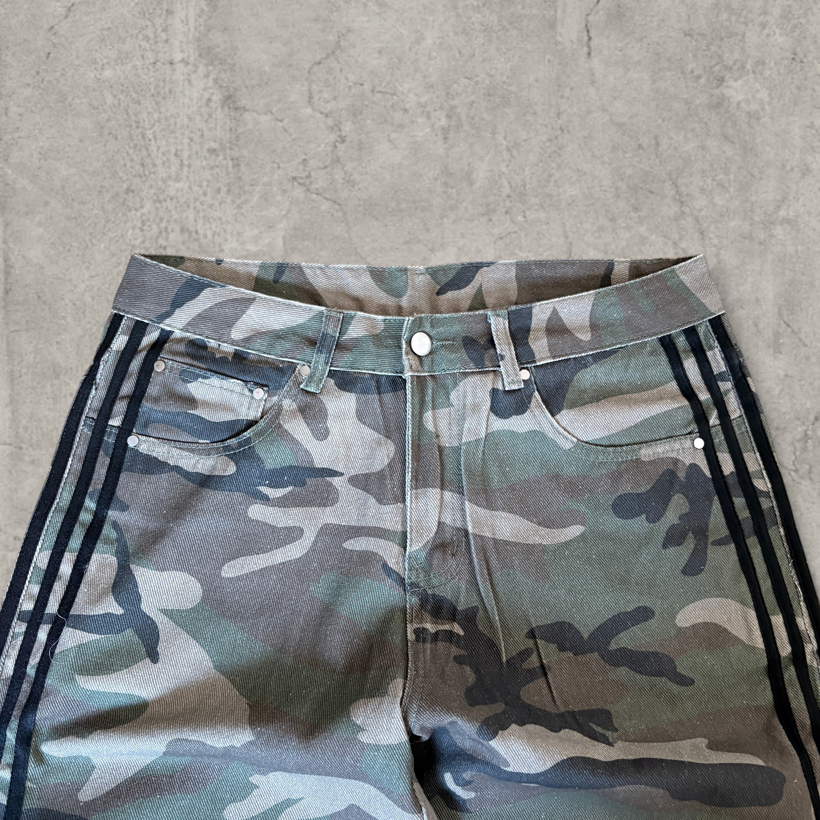 Wide-leg skater jeans with camouflage print and black stripes.