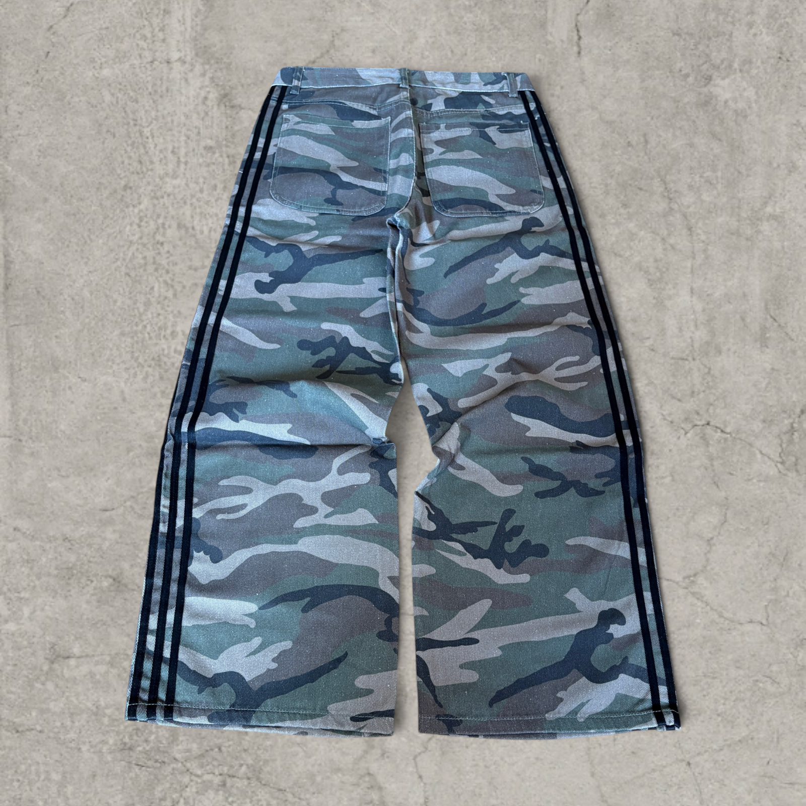 Wide-leg skater jeans with camouflage print and black stripes.