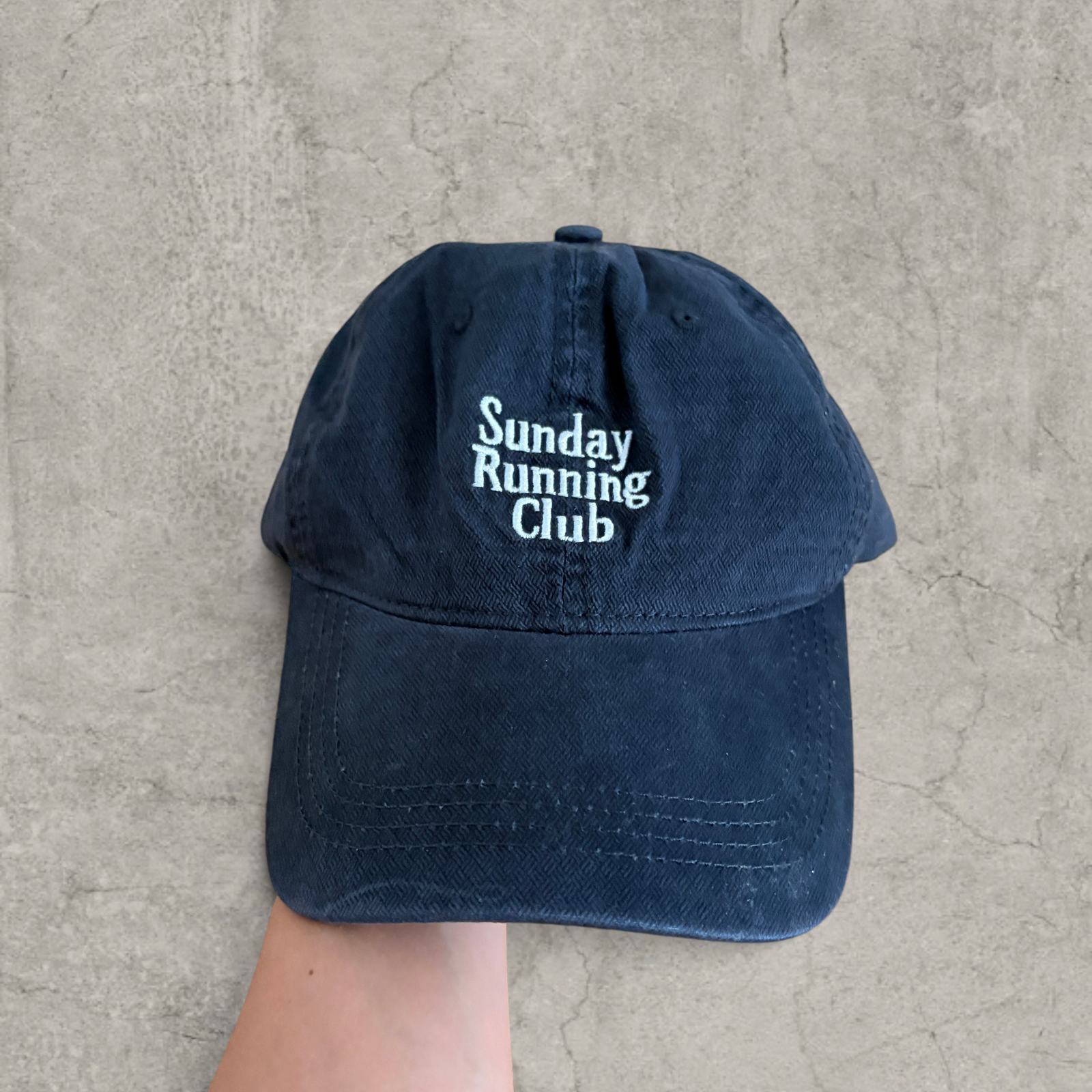 Baseball cap with Sunday Running Club logo in black.