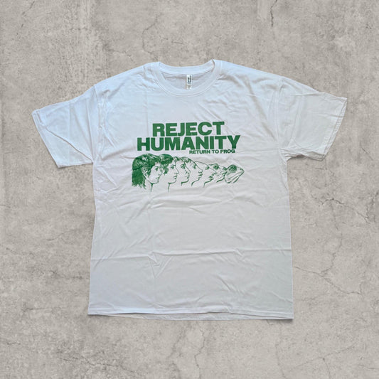 White T-shirt laid flat showing front graphic of human to frog transformation in green with 'Reject Humanity Return to Frog' text