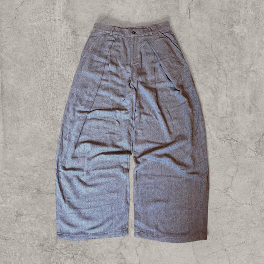 Grey beige baggy relaxed fit tailored trousers with herringbone pattern laid flat on concrete floor