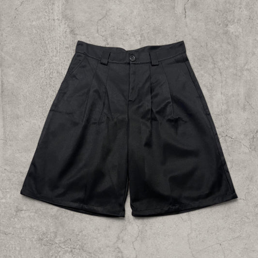 Black baggy Japanese tailored shorts with pleats laid flat showing front with button and belt loops