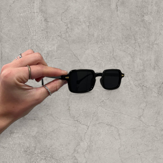 Black vintage style unisex square and rectangle tinted sunglasses held in hand showing front view