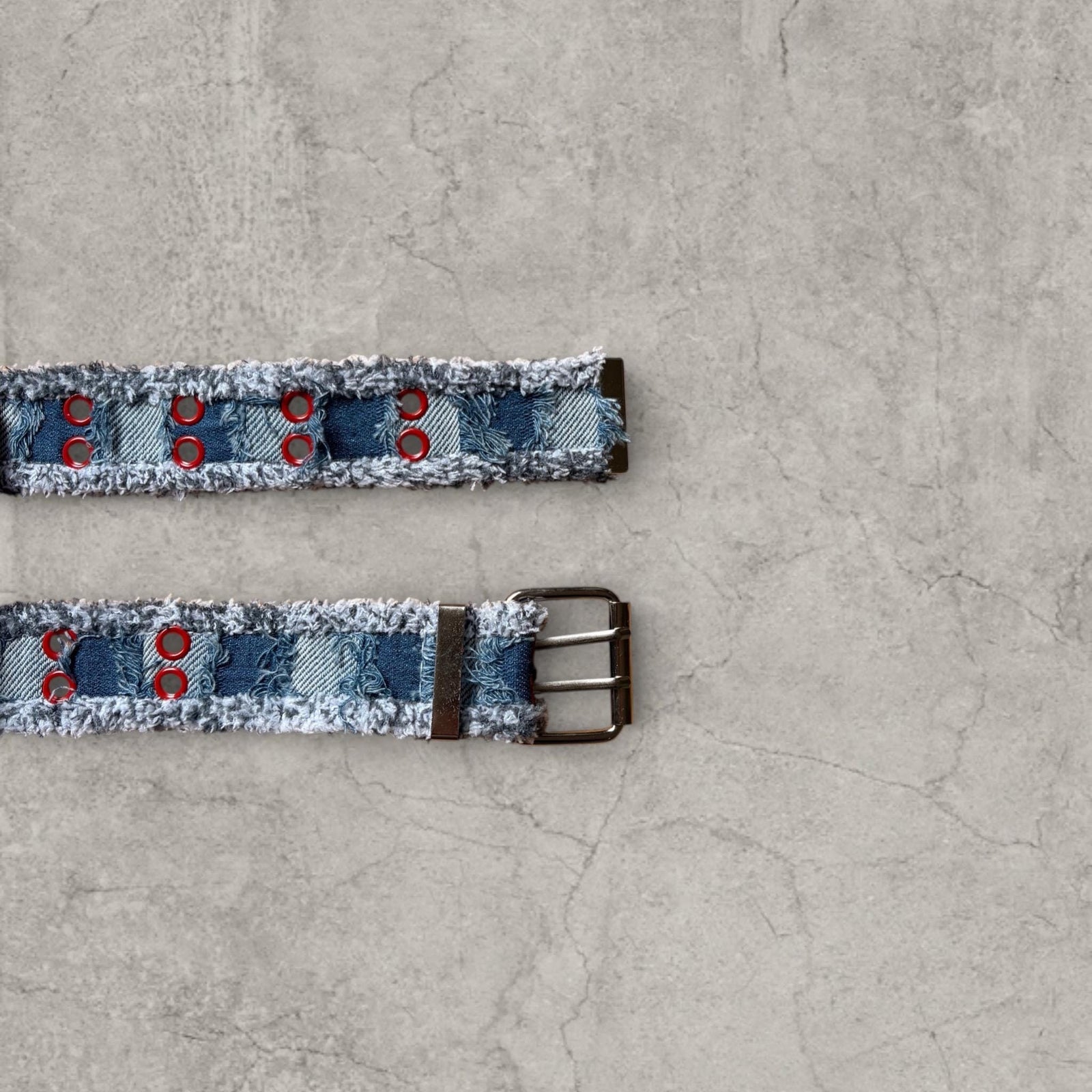 Cool distressed denim belt in navy and blue with red eyelet and silver metal buckle. Adjustable