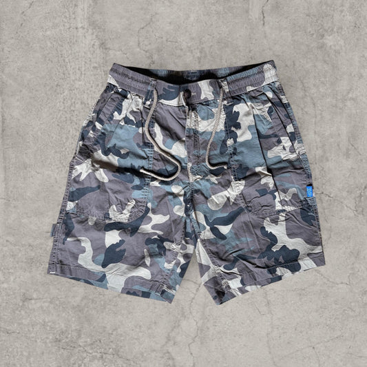 Front view of baggy relaxed fit utility shorts in khaki green beige camo with drawcord waist and pocket detailing