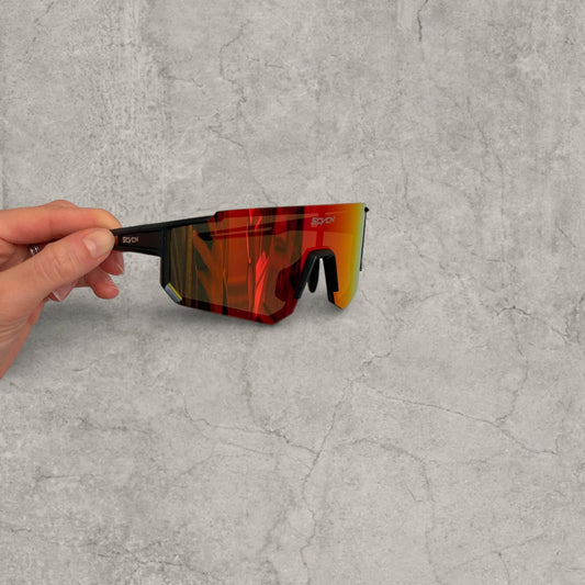 Black framed sport sunglasses with red orange yellow reflective lens held from side