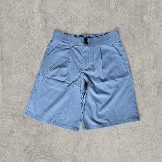 Front view of baggy pleated shorts in grey blue with button closure and side pockets