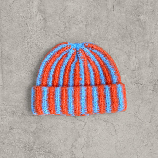 Orange and blue striped knit beanie hat with cuffed edge on grey background
