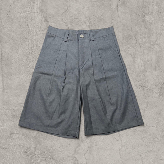 Grey baggy tailored shorts with pleats front view on concrete background