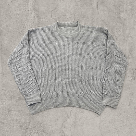 Grey knitted jumper laid flat showing front with crew neck and ribbed hem