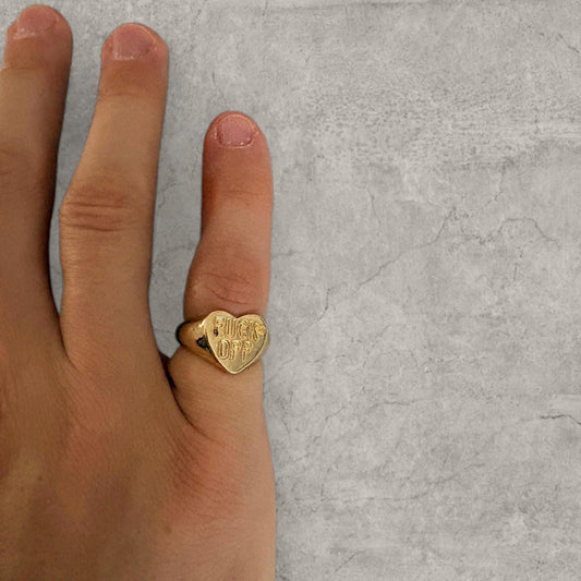 Gold colour stainless steel heart signet ring worn on finger showing engraved F off