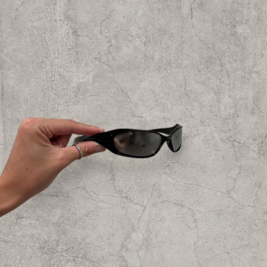 Black Insane UV400 sunglasses with silver reflective lens held in hand showing side profile