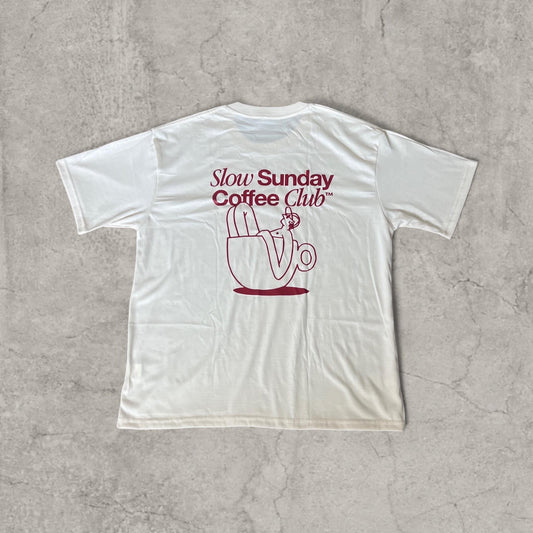 Cream T-shirt laid flat showing large burgundy Slow Sunday Coffee Club graphic on the back with figure in coffee cup