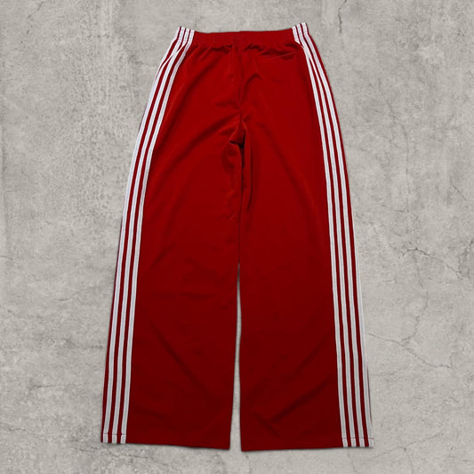 Baggy relaxed fit red trousers with white side stripes laid flat front view