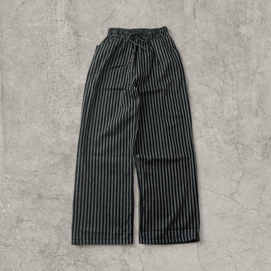 Vintage style wide-leg trousers in grey and black vertical pinstripe with drawstring waist laid flat on a grey surface