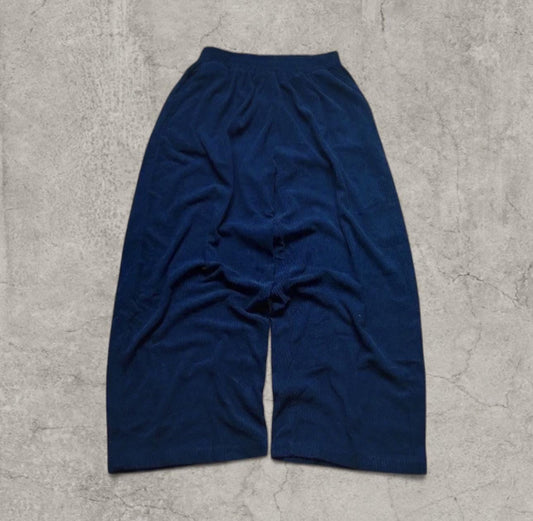 Navy corduroy wide leg trousers laid flat on a concrete floor showing front view and crease details