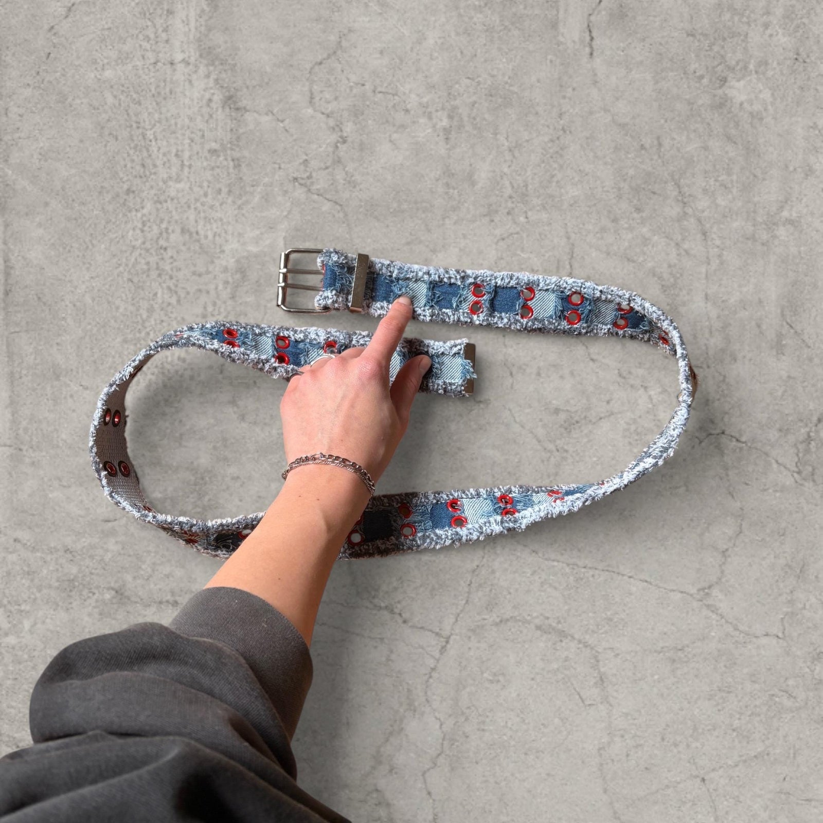 Cool distressed denim belt in navy and blue with red eyelet and silver metal buckle. Adjustable