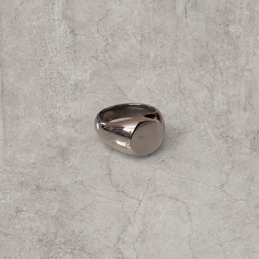Silver colour signet ring with rounded face on grey background