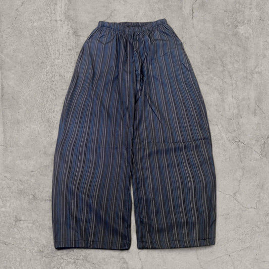Wide-leg striped trousers in navy and blue laid flat on concrete background