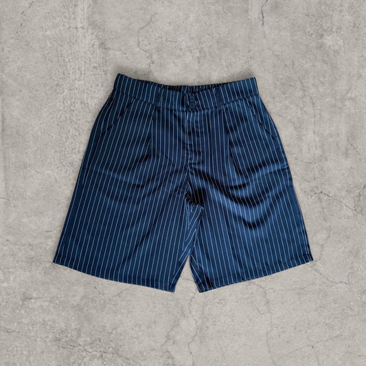Black pinstripe baggy relaxed fit shorts with pleats laid flat on concrete surface front view