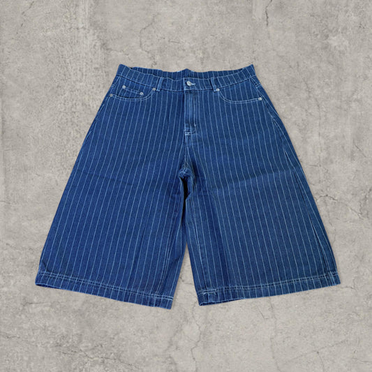 Wide leg navy blue denim jorts shorts with light blue vertical pinstripes shown flat on grey surface