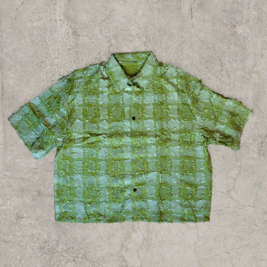 Boxy short-sleeved shirt in green with textured checkered pattern laid flat