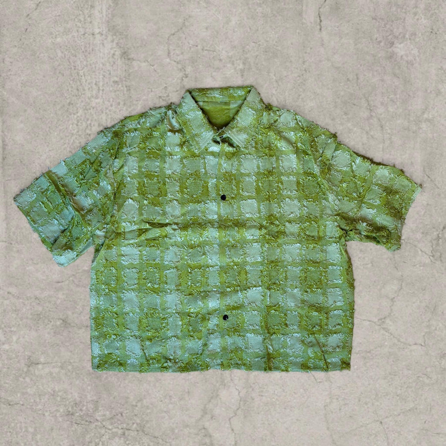 Boxy short-sleeved shirt in green with textured checkered pattern laid flat