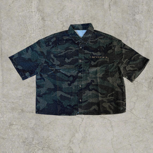 Boxy short-sleeved shirt in textured khaki camo with leopard pocket laid flat on concrete