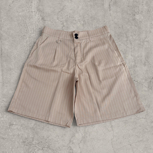 Cream baggy shorts with white pinstripe and front pleats laid flat on concrete