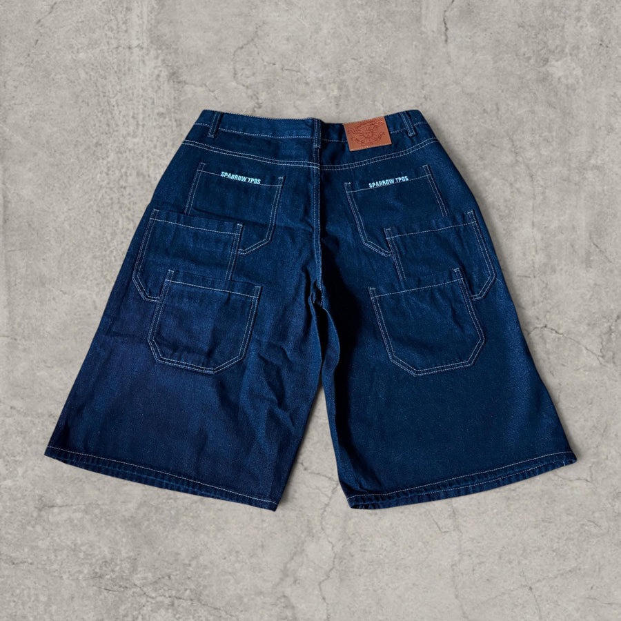 Back view of navy blue baggy denim jorts shorts showing multiple patch pockets and leather patch label