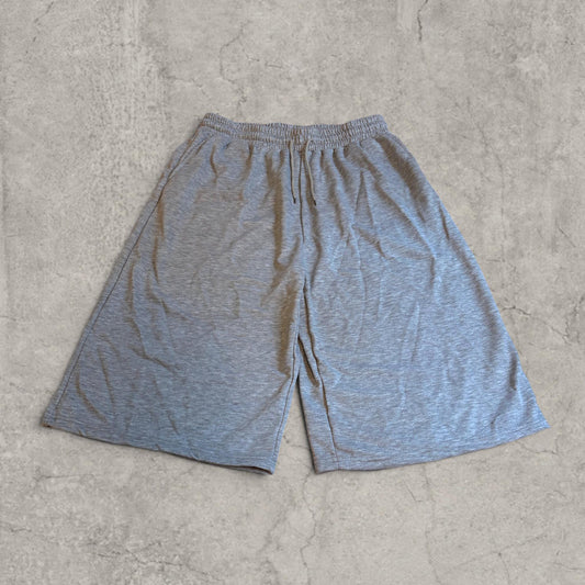 Grey wide leg jersey shorts laid flat on a grey surface