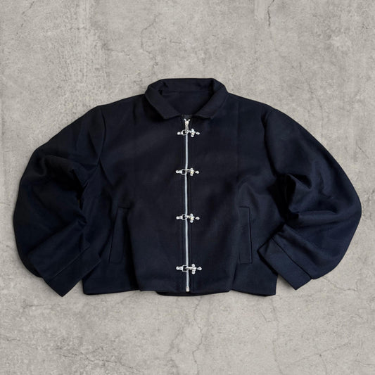 Vintage black felt bomber jacket with silver clasps and zip laid flat on concrete