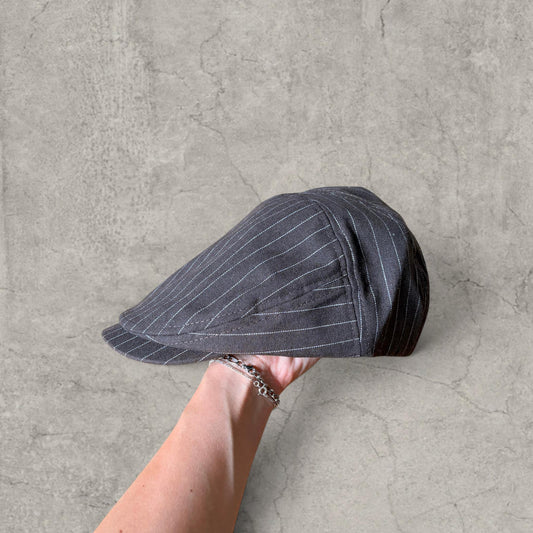Brown flat peak beret cap with pinstripe held in hand showing side view