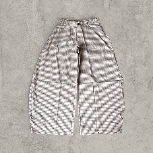 Cream wide-leg trousers with brown and black check pattern laid flat on a grey surface front view