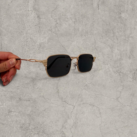 Gold grey Insane UV400 sunglasses with black lenses and metal straight arms held against a grey background