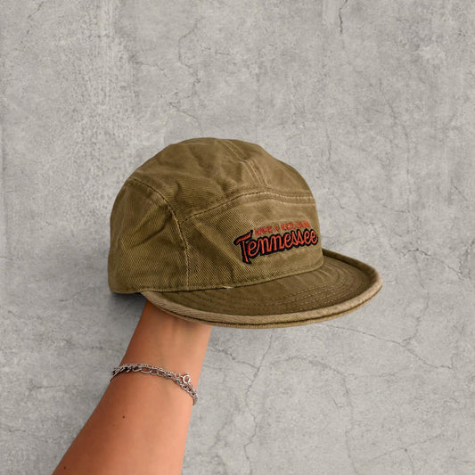 Beige vintage style baseball cap with red and white Tennessee logo held in hand against a grey concrete background